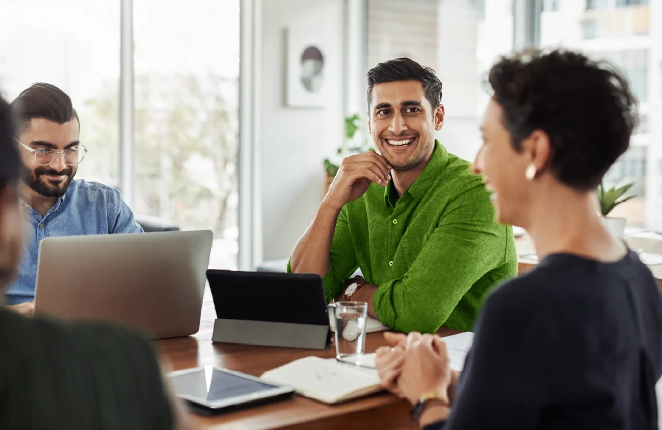 a group at an office desk smiling at their meeting